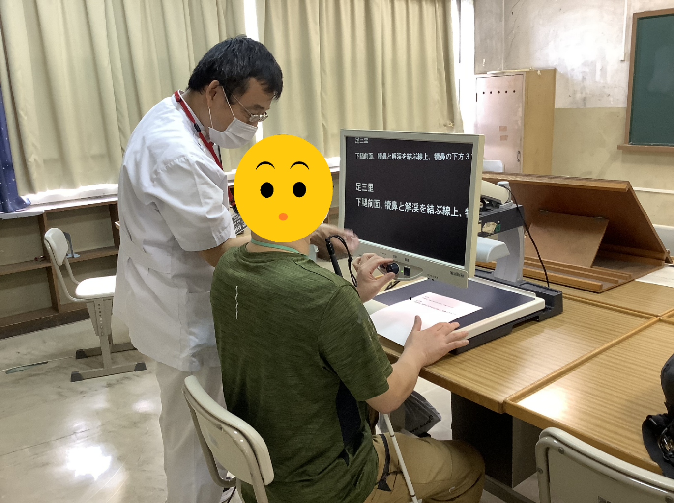 画像 拡大読書器でツボの教科書を見る参加者