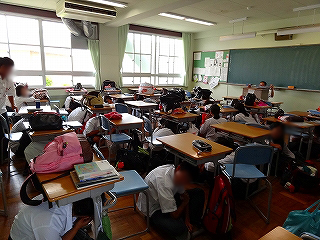 地震の想定で机の下に頭を隠す生徒達